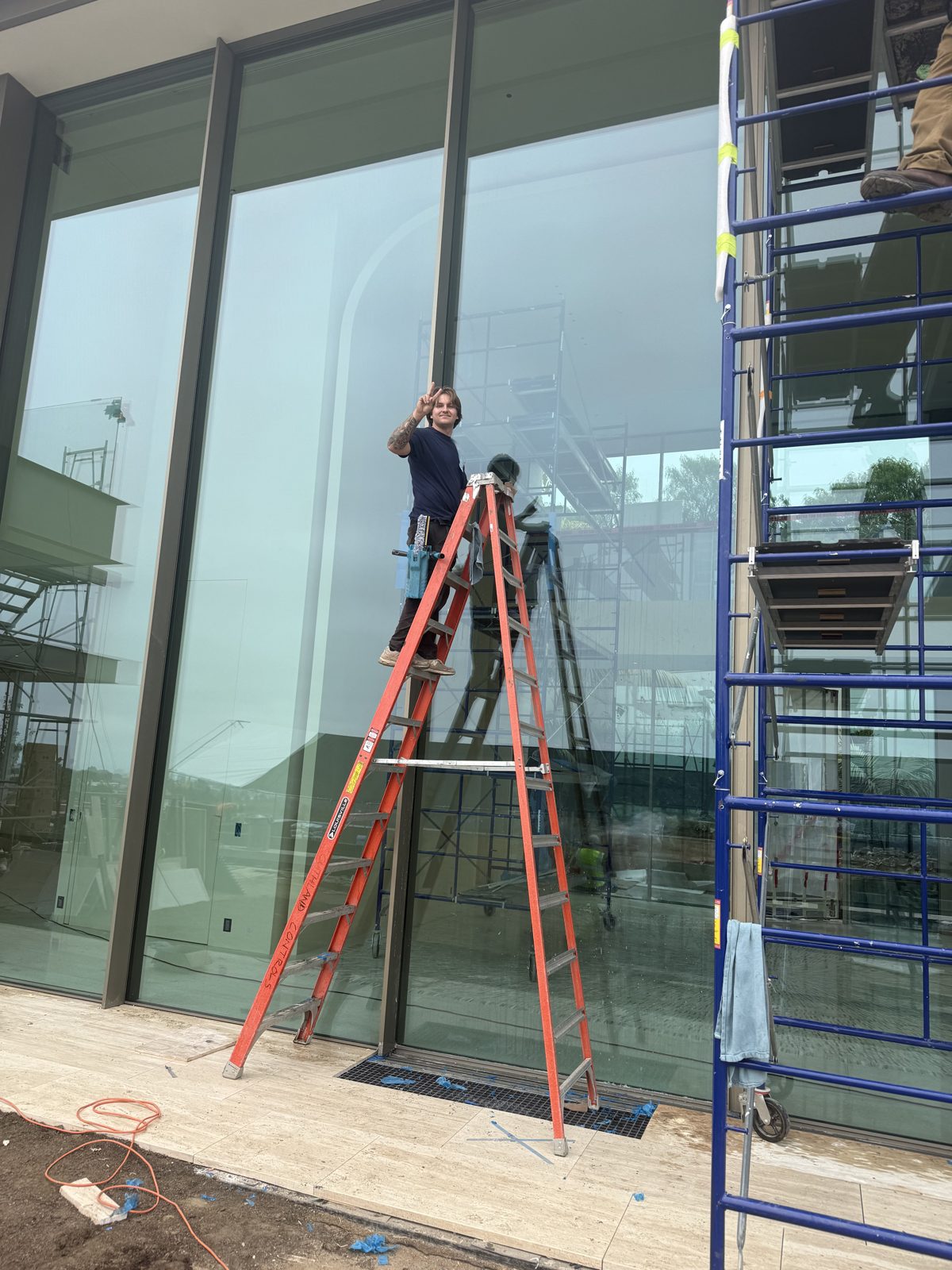 Technician cleaning tall glass with a ladder